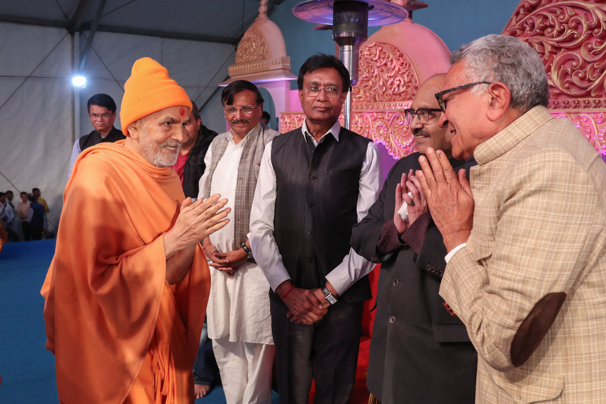 Swamishri greets invited guests on stage