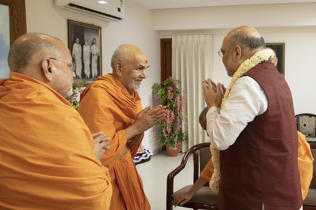 HH Mahant Swami Maharaj and Pujya Ishwarcharan Swami welcome Shri Amit Shah with a garland